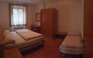 a bedroom with two beds and a cabinet and a window at Appartamento Emma in Molveno