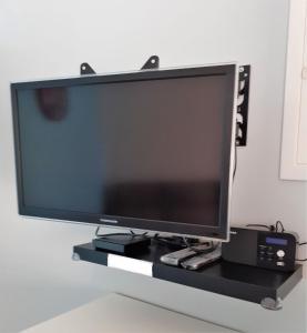 a flat screen tv sitting on a black shelf at Meublé classé 3 étoiles in Saint-Brieuc