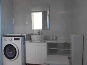 a white kitchen with a washing machine and a sink at Glikeria Loft Apartment in Volos