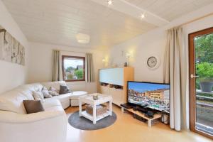 sala de estar con sofá blanco y TV grande en Ferienhaus Anne mit Sauna, See, Wald und Ruhe en Kirchheim