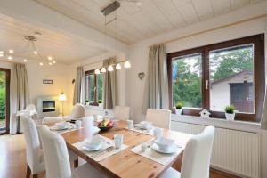 uma sala de jantar com uma mesa de madeira e cadeiras brancas em Ferienhaus Anne mit Sauna, See, Wald und Ruhe em Kirchheim