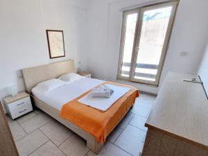 a bedroom with a bed with an orange blanket and a window at Sea - View in Himare