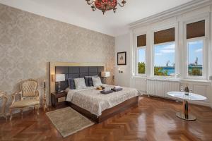 a bedroom with a bed and a table and two windows at Villa Muenz Luxurious Residence in Pula