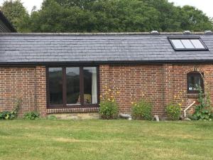 une maison en briques avec une fenêtre et un toit dans l'établissement The Woodshed, à Warnford