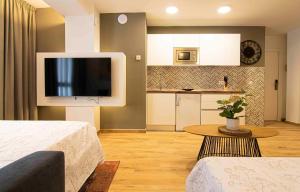 sala de estar con 2 camas y cocina pequeña en Apartamentos Leonor, en Málaga