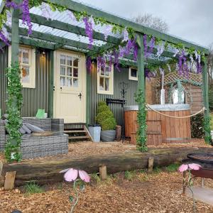 a pergola in front of a house with purple flowers at Little Oakhurst in Clitheroe