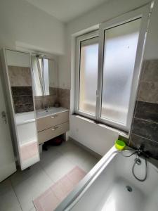 La salle de bains est pourvue d'une baignoire, d'un lavabo et d'une fenêtre. dans l'établissement Bel Appartement 3 étoiles 6 pers 3 pièces 60m2 idéalement placé, à Cabourg