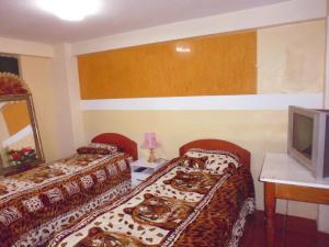 Habitación de hotel con 2 camas y TV en Hospedaje Pumacurco Betty, en Cusco
