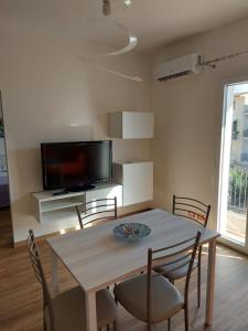 a dining room with a table and chairs and a tv at Alice apartment in Salemi