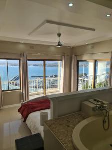 a bedroom with a bed and a tub and windows at Bikini Beach Manor in Gordonʼs Bay