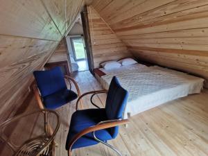 sypialnia z łóżkiem i krzesłami w drewnianym domku w obiekcie Przystan Ramotowo w Lidzbarku Warmińskim