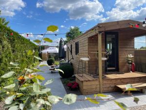 a small wooden cabin in a garden with a patio at Roulotte du puits avec jacuzzi et sauna privatif 