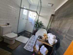 uma casa de banho com um WC, um chuveiro e um lavatório. em Pousada Lugama em Bento Gonçalves