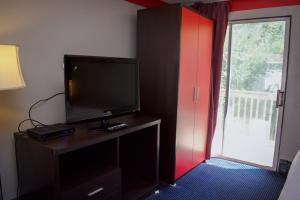 a room with a television on a dresser with a sliding glass door at Travel inn in North Kingstown