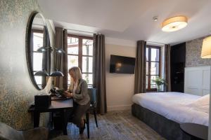 une femme assise à un bureau dans une chambre d'hôtel dans l'établissement Hôtel-Restaurant du Mouton, à Ribeauvillé