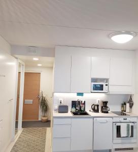 a white kitchen with white cabinets and appliances at Lovely new city apartment all amenities in Seinäjoki