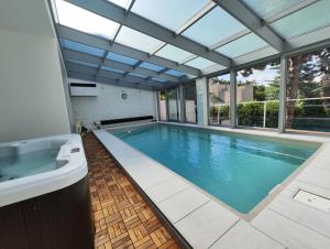 an indoor swimming pool with a glass ceiling and a tub at Vila Prag in Prague