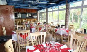 un comedor con mesas, sillas y ventanas en Moonlight Beach Villa, en La Digue