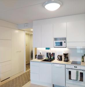 a kitchen with white cabinets and a microwave at Lovely new city apartment all amenities in Seinäjoki