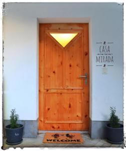 een houten deur in een wit gebouw met twee potplanten bij Casa Mirada in Trin