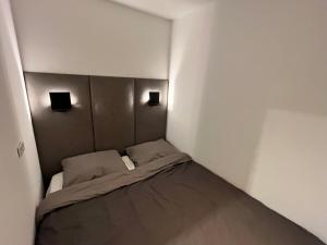 Cama pequeña en habitación pequeña con 2 lámparas en Alpen Studio Ellmau I, en Ellmau
