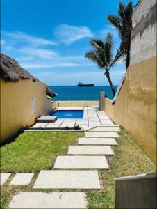 un chemin menant à une maison avec l'océan en arrière-plan dans l'établissement Hermoso condominio con alberca y club de playa!!, à Manzanillo