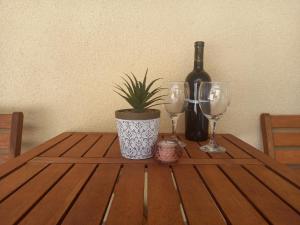 a table with two wine glasses and a plant on it at Apartman Maja in Kaštela