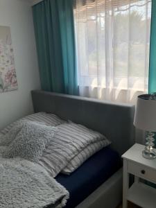 a bed in a bedroom with a window with a blanket at Apartament Maria in Gietrzwałd