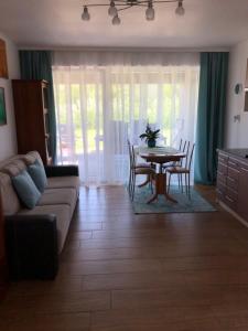 ein Wohnzimmer mit einem Sofa, einem Tisch und Stühlen in der Unterkunft Apartament Maria in Gietrzwałd