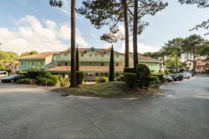 un grand bâtiment avec des voitures garées dans un parking dans l'établissement Appartement sur golf avec piscine chauffée à Lacanau-Océan, à Lacanau