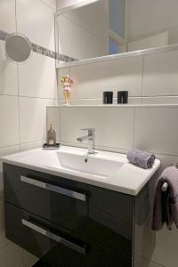 uma casa de banho branca com um lavatório e um espelho em Ferienwohnung Domicile chic mit Schwimmbad und Saunanutzung em Bad Harzburg