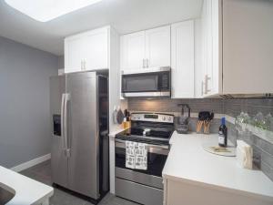 a kitchen with white cabinets and a stainless steel refrigerator at Homey Bungalow Convenient to Marietta and I-75! in Marietta
