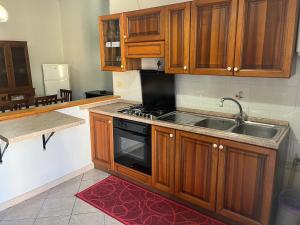 a kitchen with wooden cabinets and a stove and a sink at Dimora dei Poli Ferrero - Spaziosa casa indipendente, vista mare, in centro su corso Garibaldi in Serracapriola +21 photos