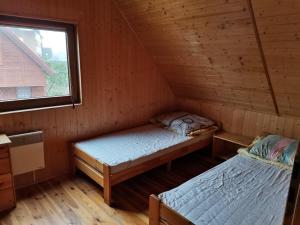 two beds in a wooden room with a window at Ala i Tomek domki in Łeba