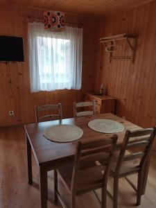 una mesa de madera y sillas en una habitación con ventana en Ala i Tomek domki, en Łeba