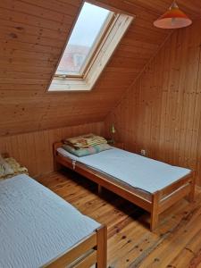 two beds in a wooden room with a window at Ala i Tomek domki in Łeba