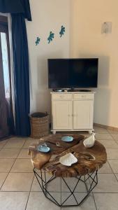 sala de estar con mesa de centro de madera y TV de pantalla plana en Casa Souad, a cheerful and charming beach view 2 bedroom house and free parking, en Porto San Paolo