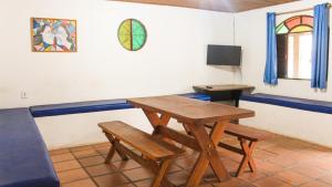 Zimmer mit einem Tisch, 2 Bänken und einem TV in der Unterkunft 4 Estações Arraial - Casa Verde in Arraial do Cabo