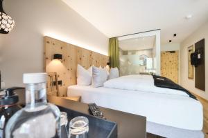 ein Schlafzimmer mit einem großen weißen Bett und einem Spiegel in der Unterkunft Hotel die Arlbergerin ADULTS FRIENDLY 4 STAR in Sankt Anton am Arlberg