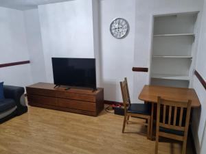 uma sala de estar com uma televisão, uma mesa e um relógio em Homie em Aberdeen
