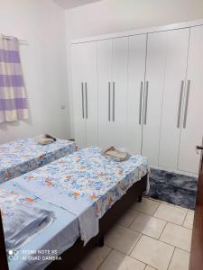 a bedroom with two beds and white cabinets at Casa Agradável próxima ao Bosque in Pôrto Feliz