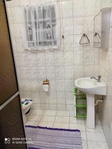 a white bathroom with a sink and a toilet at Casa Agradável próxima ao Bosque in Pôrto Feliz