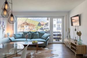 a living room with a blue couch and a table at Design Apartment „Alpenglühen“ nahe Breitachklamm in Oberstdorf