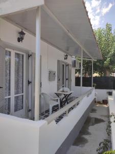 a white house with a table and chairs on the porch at Victory's house, 3min walk to Skala's sandy beach in Skala