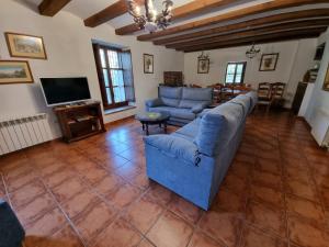 Sala de estar con 2 sofás azules y TV en Masia MATUTANO en Villafranca del Cid