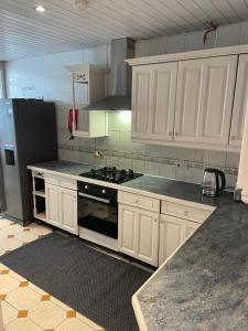 a kitchen with white cabinets and a stove and a refrigerator at Wembley Rooms in London