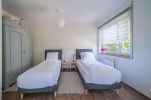 two beds sitting in a room with a window at Cosy Home in South Alsace for work and leisure in Pfastatt