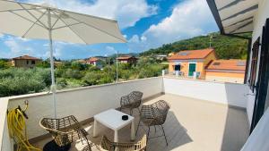 balcón con mesa, sillas y sombrilla en Villa Flora Affittacamere, en Luni