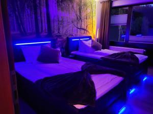 two beds in a dark room with purple lights at Hotel Seeblick am Sankelmarker See - Natur und Erholung in Oeversee