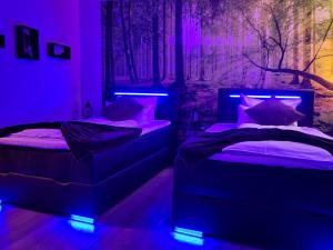 two twin beds in a room with purple lights at Hotel Seeblick am Sankelmarker See - Natur und Erholung in Oeversee